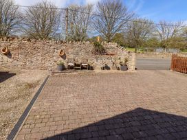 An outdoor area with stone wall and wooden chairs at Willow cottage in Seahouses