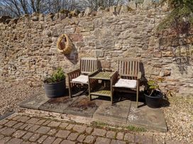 An outdoor seating area with wooden chairs and a table at Willow cottage Seahouses