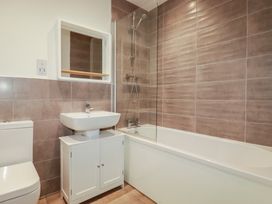 A bathroom with a toilet, sink, mirror, shower, and bathtub at Cwtch Treth in Newquay