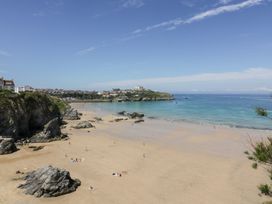A beach view with cliffs and people at Cwtch Treth in Newquay