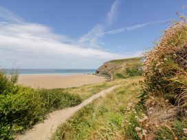 A beach with a pathway leading to the ocean at Cwtch Treth in Newquay