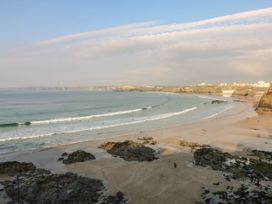 A beach with waves and people at Cwtch Treth in Newquay