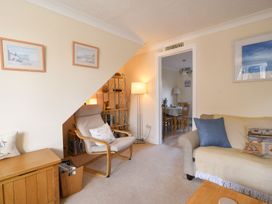 A living room with an armchair and bookshelf at Mead Cottage in Bridport