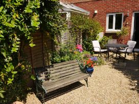 A garden with a bench, table, and chairs at Mead Cottage in Bridport