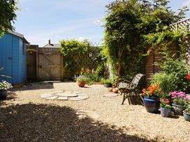 A garden with gravel, bench, flower pots and a shed at Mead Cottage in Bridport
