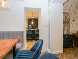A dining area with a table and chairs looking into a kitchen at The Old Post Office in Whitehaven