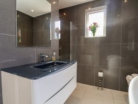 A bathroom with a sink, mirror, shower, and toilet at 30 Prospect Hill in Whitby