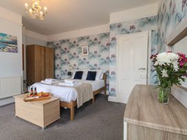 A bedroom with beds, wardrobe and flowers at 30 Prospect Hill in Whitby