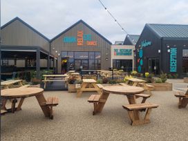 An outdoor area with wooden tables and colorful chairs at St Osyth- Sleeps8-freeparking-wifi-holidaypark, Clacton-On-Sea