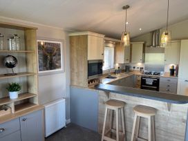 A kitchen with a sink, stools, and cabinetry at Yorkshire view lodge in Wilberfoss