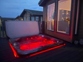 A hot tub on a deck outside a building at Yorkshire view lodge in Wilberfoss