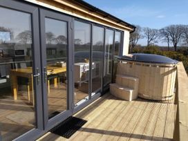A deck with a hot tub and outdoor seating at Cleeves Cabins 2, Arran Luxury Lodge with hot tub in St. John's Town Of Dalry