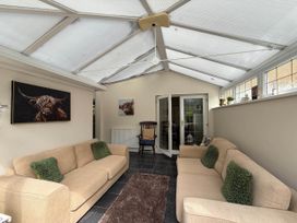 A conservatory with two sofas and an armchair at 3 Bed House - Sleeps 6 - Parking - Garden - Wifi Glynneath