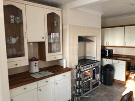 A kitchen with cabinets, stove, and microwave at 3 Bed House - Sleeps 6 - Parking - Garden - Wifi Glynneath