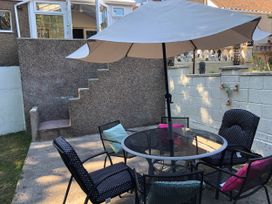 A garden with a table and chairs shaded by an umbrella at 3 Bed House - Sleeps 6 - Parking - Garden - Wifi Glynneath