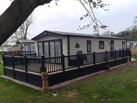 An outdoor area with a lodge and decking at 2 Bed Lodge Sleeps 4 - Pet Welcome - Fireplace in Cirencester