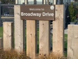 A welcome sign for Broadway Drive with a wooden fence in an outdoor area