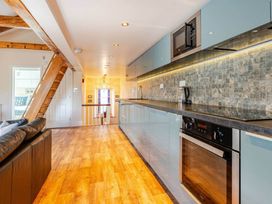 A kitchen with modern appliances and a wooden staircase at Sedbergh Penthouse - KingBed - Tv - Wifi Sedbergh