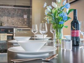 A dining room table set with plates, glasses, and a wine bottle at Sedbergh Penthouse - KingBed - Tv - Wifi Sedbergh