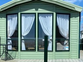 A green building with large windows and curtains at Beachside Lodge - Sleeps 6 - Pets ok - Parking in Heysham