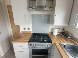 A kitchen with stove, oven, sink, and cupboard at Beachside Lodge - Sleeps 6 - Pets ok - Parking in Heysham