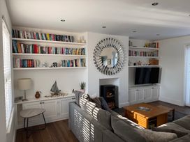 A living room with a bookshelf, tv, and fireplace at Lorrell in Salcombe