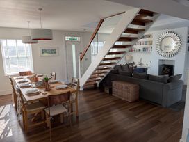 A dining room with a table set for meals and a staircase at Lorrell Salcombe