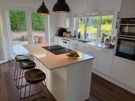 A kitchen with an island and bar stools at Lorrell in Salcombe