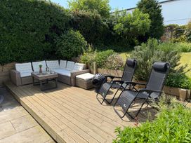 A garden with a sofa, coffee table, and sun loungers at Lorrell in Salcombe