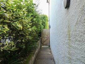 A pathway next to a wall with bushes and a gate at Lorrell in Salcombe