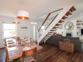A dining room with a table set for dinner and a staircase at Lorrell in Salcombe