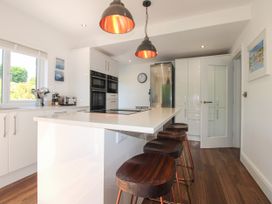 A kitchen with a countertop island and bar stools at Lorrell in Salcombe