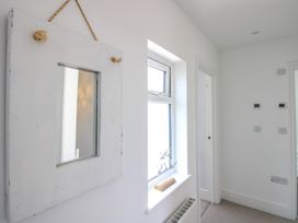 A hallway with a mirror and window at Lorrell in Salcombe