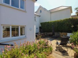 A garden with decking and chairs at Lorrell Salcombe