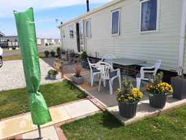 An outdoor area with a table, chairs, and flower planters at Taid's Retreat Silversands Cove beach lossiemouth