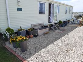 An outdoor area with a caravan, bench, and flower planters at Taid's Retreat Silversands Cove beach lossiemouth