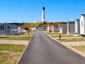 A path lined with holiday homes and a lighthouse at Taid's Retreat Silversands Cove beach lossiemouth