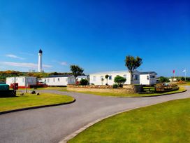 A view of caravans and a lighthouse at Taid's Retreat Silversands Cove beach lossiemouth Lossiemouth