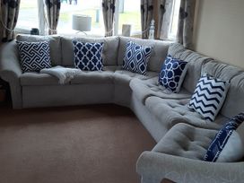 A sofa with cushions in a living room at Taid's Retreat Silversands Cove beach lossiemouth