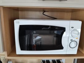 A microwave oven on a shelf at Taid's Retreat Silversands Cove beach lossiemouth