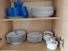 A kitchen cabinet with stacked cups and plates at Taid's Retreat Silversands Cove beach lossiemouth