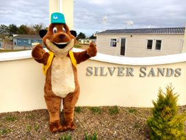 A mascot standing by the Silver Sands sign at Taid's Retreat Silversands Cove beach lossiemouth