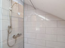 A shower with glass panel and tiles at Kiloran in Rhosneigr