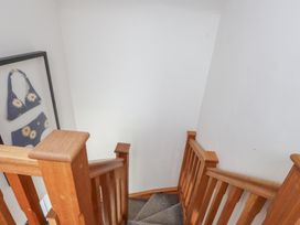 A staircase with wooden railing and framed artwork at Kiloran in Rhosneigr