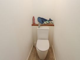 A bathroom with a toilet and decorative items at Kiloran in Rhosneigr