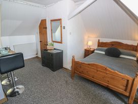A bedroom with a wooden bed and a chest of drawers at Seaside Steps in Goodwick