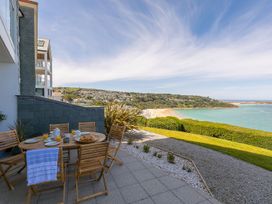 An outdoor area with a table and chairs overlooking a beach at Anchors Rest in St. Ives