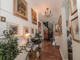 A hallway with paintings on the wall and a staircase at 7 The Cedars Wotton-Under-Edge