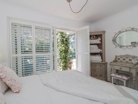 A bedroom with a bed and window opening to a garden at 7 The Cedars Wotton-Under-Edge
