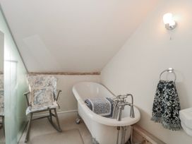 A bathroom with a bathtub, chair and towel rack at 7 The Cedars Wotton-Under-Edge